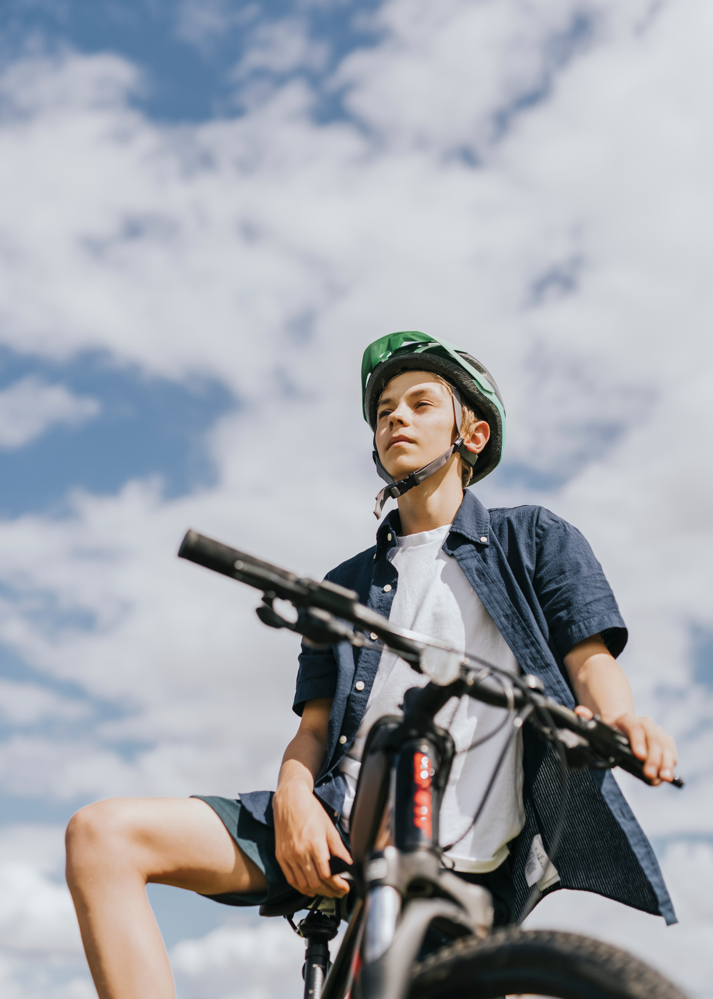 A teenager with a bike looking upward